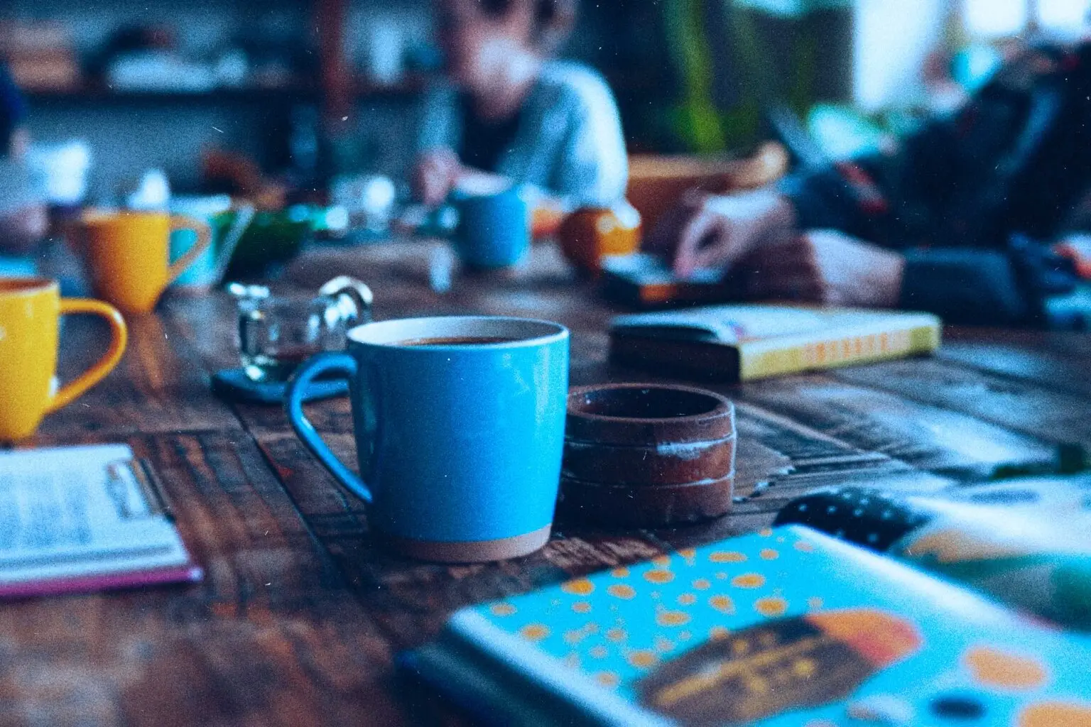 coffee and books on a table with blurred people on the edges