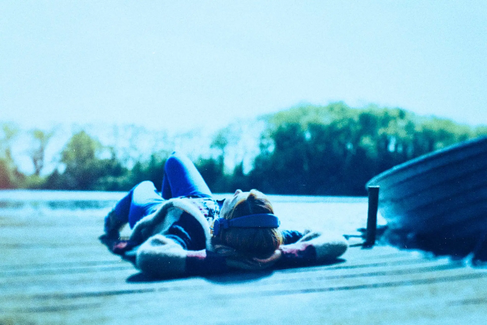 girl laying on dock wearing headphones